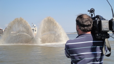 Photo of a man with a camera, filming dredge disposal on the Mississippi River