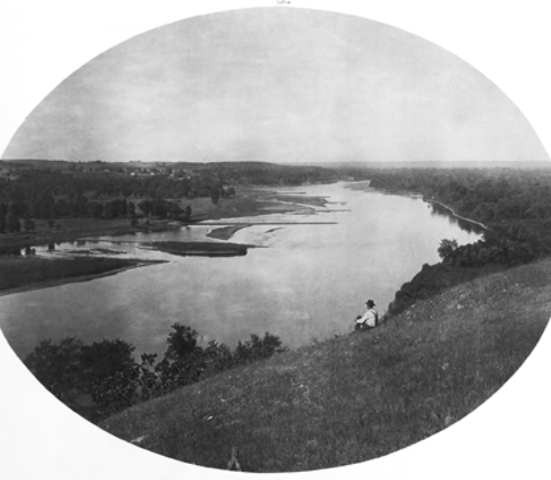 Historic black and white photo of a man overlooking the Mississippi River from a bluff.